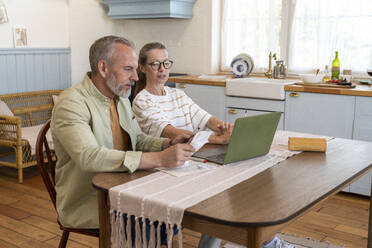 Couple discussing over financial bills sitting at table at home - VPIF08387