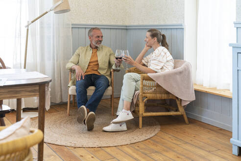 Ehepaar genießt Wein auf einem Stuhl sitzend zu Hause - VPIF08394