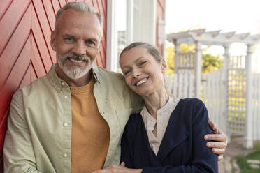 Smiling man with arm around woman near house - VPIF08414