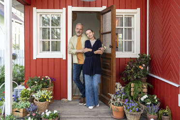Älteres Paar steht in der Nähe von Pflanzen an der Haustür - VPIF08416