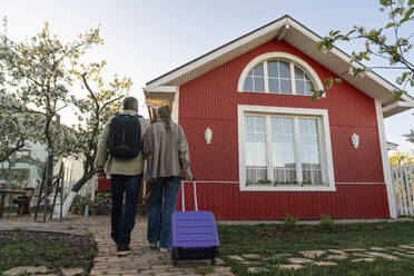 Ehepaar mit Gepäck bei der Ankunft am Haus - VPIF08441