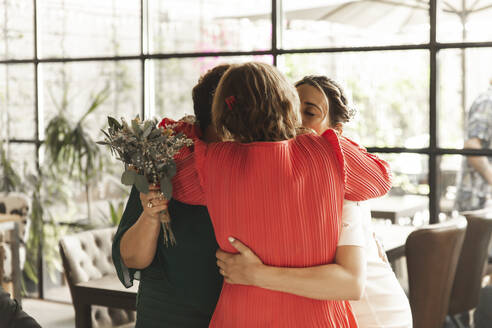 Emotional family hugging bride at wedding reception - PCLF00656