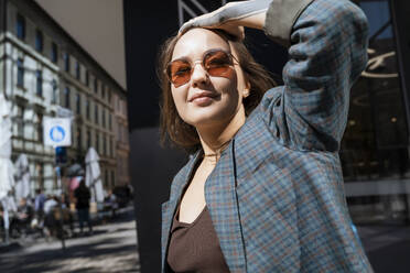 Lächelnde Frau mit Sonnenbrille an einem sonnigen Tag - NDEF00966