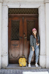 Smiling woman with backpack standing in front of door - NDEF00970