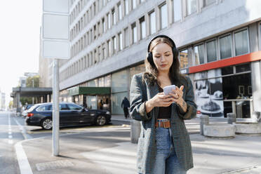 Frau benutzt Smartphone in der Nähe eines Gebäudes in der Stadt - NDEF00983