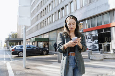 Woman using smart phone near building in city - NDEF00983