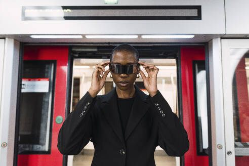 Junge Frau mit intelligenter Brille vor der U-Bahn stehend - PNAF05988