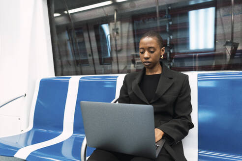 Junge Geschäftsfrau mit Laptop in der U-Bahn - PNAF05998