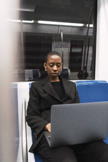 Geschäftsfrau arbeitet an einem Laptop in der U-Bahn - PNAF06000