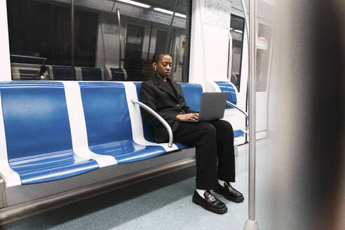 Geschäftsfrau mit Laptop und sitzend in der U-Bahn - PNAF06001