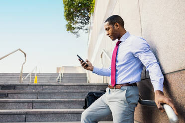 Handsome male african american business man CEO in a stylish corporate elegant suit in a business center outdoors - Black male commuter going to work, city and financial district in the background - DMDF01554