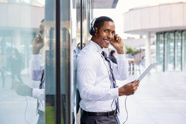 Handsome male african american business man CEO in a stylish corporate elegant suit in a business center outdoors - Black male commuter going to work, city and financial district in the background - DMDF01564