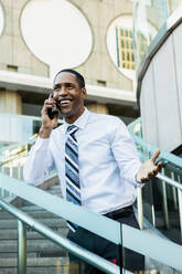 Handsome male african american business man CEO in a stylish corporate elegant suit in a business center outdoors - Black male commuter going to work, city and financial district in the background - DMDF01571