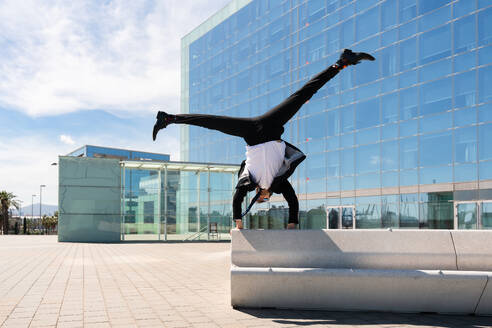 Happy and handsome adult businessman wearing elegant suit doing acrobatic trick moves in the city, alternative concept for business advertisement with energetic and creative people - DMDF01587