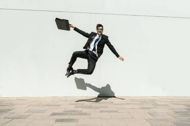 Happy and handsome adult businessman wearing elegant suit doing acrobatic trick moves in the city, alternative concept for business advertisement with energetic and creative people - DMDF01594