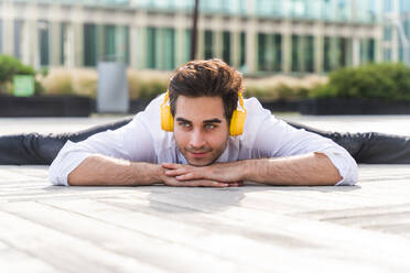 Happy and handsome adult businessman wearing elegant suit doing acrobatic trick moves in the city, alternative concept for business advertisement with energetic and creative people - DMDF01614