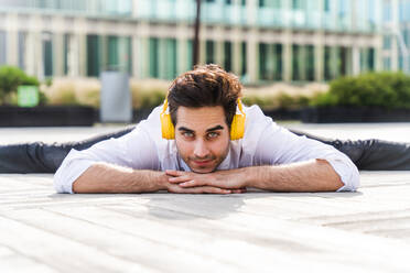 Happy and handsome adult businessman wearing elegant suit doing acrobatic trick moves in the city, alternative concept for business advertisement with energetic and creative people - DMDF01615