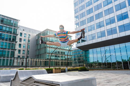 Happy and handsome adult businessman wearing elegant suit doing acrobatic trick moves in the city, alternative concept for business advertisement with energetic and creative people - DMDF01620