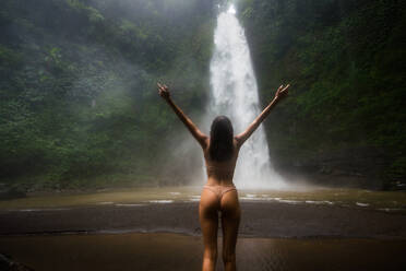 Beautiful young woman posing at the great Sekumpul waterfall in the deep rainforest of Bali island, Indonesia. - DMDF01684