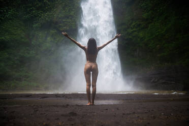 Beautiful young woman posing at the great Sekumpul waterfall in the deep rainforest of Bali island, Indonesia. - DMDF01685