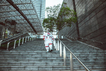 Spaceman in a futuristic station. Man with space suit walking in an urban area - DMDF01765