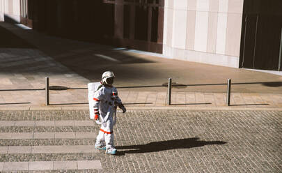 Raumfahrer in einer futuristischen Station. Astronaut mit Raumanzug geht in einem städtischen Gebiet spazieren - DMDF01770