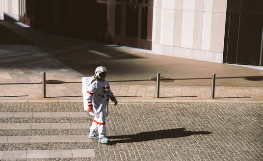 Raumfahrer in einer futuristischen Station. Astronaut mit Raumanzug geht in einem städtischen Gebiet spazieren - DMDF01770