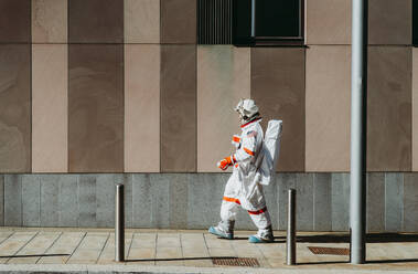 Raumfahrer in einer futuristischen Station. Astronaut mit Raumanzug geht in einem städtischen Gebiet spazieren - DMDF01771