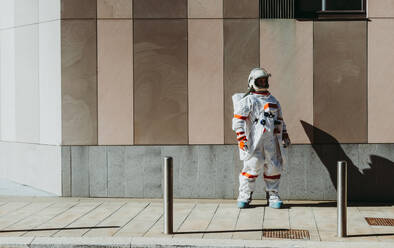 Raumfahrer in einer futuristischen Station. Astronaut mit Raumanzug geht in einem städtischen Gebiet spazieren - DMDF01773