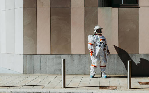 Raumfahrer in einer futuristischen Station. Astronaut mit Raumanzug geht in einem städtischen Gebiet spazieren - DMDF01773