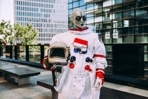 Alien-Raumfahrer in einer futuristischen Station. Astronaut mit Raumanzug geht in einem städtischen Gebiet spazieren - DMDF01776