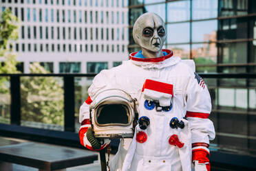 Alien-Raumfahrer in einer futuristischen Station. Astronaut mit Raumanzug geht in einem städtischen Gebiet spazieren - DMDF01777