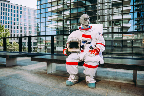 Alien-Raumfahrer in einer futuristischen Station. Astronaut mit Raumanzug geht in einem städtischen Gebiet spazieren - DMDF01779