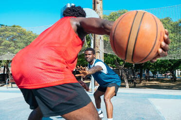 Ein Basketballspiel, bei dem einer gegen den anderen auf dem Platz trainiert. Filmische Darstellung von Freunden, die Schüsse und Slam Dunks in einem städtischen Gebiet üben - DMDF01781