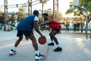 One vs one basketball game training at the court. Cinematic look image of friends practicing shots and slam dunks in an urban area - DMDF01786