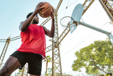 Junger Basketballspieler, der auf dem Platz trainiert. Filmische Darstellung eines Mannes, der in einem städtischen Gebiet Schüsse und Slam Dunks übt - DMDF01797