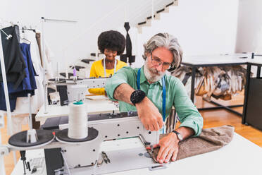 Multiethnic team of fashion designers working in a clothing start-up workshop - Multiracial group of stylists, tailor designers and dressmakers working on a new collection - DMDF01810