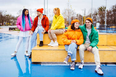 Multiracial group of young happy friends meeting outdoors in winter, wearing winter jackets and having fun - Multiethnic millennials bonding in a urban area, concepts about youth and social releationships - DMDF01863