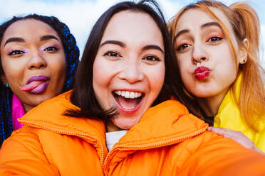 Multiracial group of young happy friends meeting outdoors in winter, wearing winter jackets and having fun - Multiethnic millennials bonding in a urban area, concepts about youth and social releationships - DMDF01931