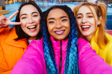 Multiracial group of young happy friends meeting outdoors in winter, wearing winter jackets and having fun - Multiethnic millennials bonding in a urban area, concepts about youth and social releationships - DMDF01933