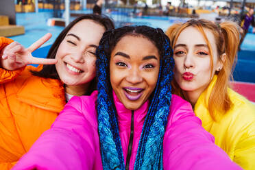 Multiracial group of young happy friends meeting outdoors in winter, wearing winter jackets and having fun - Multiethnic millennials bonding in a urban area, concepts about youth and social releationships - DMDF01934