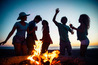 Multicultural group of friends partying on the beach - Young people celebrating during summer vacation, summertime and holidays concepts - DMDF01973