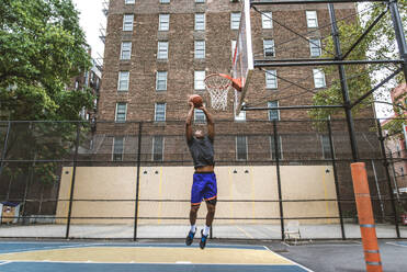 Afro-american basketball player training on a court in New York - Sportive man playing basket outdoors - DMDF01977