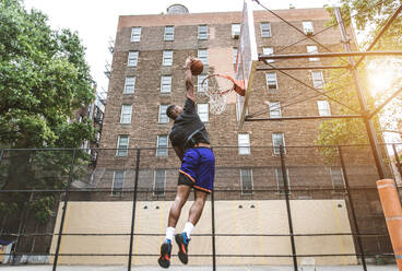 Afro-american basketball player training on a court in New York - Sportive man playing basket outdoors - DMDF01979