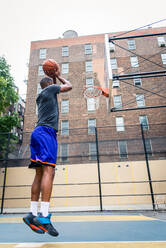 Afro-american basketball player training on a court in New York - Sportive man playing basket outdoors - DMDF01981