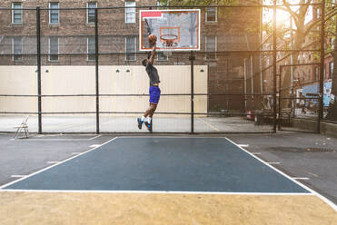 Afro-american basketball player training on a court in New York - Sportive man playing basket outdoors - DMDF01987