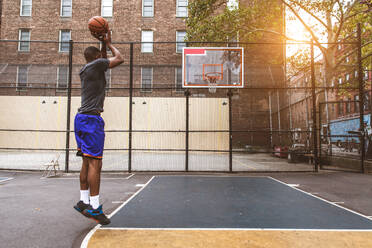 Afro-american basketball player training on a court in New York - Sportive man playing basket outdoors - DMDF01988