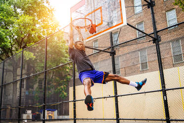 Afro-american basketball player training on a court in New York - Sportive man playing basket outdoors - DMDF01997