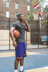 Afro-american basketball player training on a court in New York - Sportive man playing basket outdoors - DMDF02000