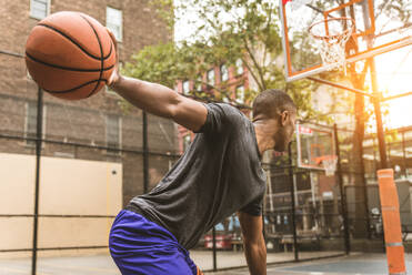 Afro-american basketball player training on a court in New York - Sportive man playing basket outdoors - DMDF02003